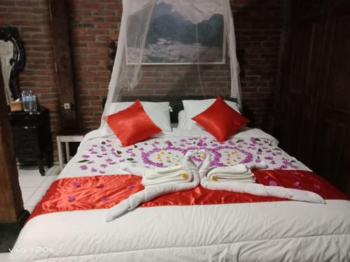 日惹Villa Mak Cik的一张铺有红白床单和红色枕头的床
