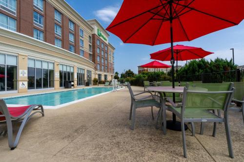 默夫里斯伯勒Holiday Inn Murfreesboro, an IHG Hotel的庭院配有桌椅和红色遮阳伞