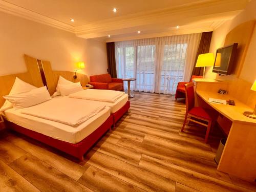 HeimbuchenthalLandhotel Heimathenhof的配有一张床和一张书桌的酒店客房