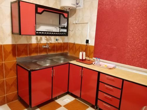 Dawmat al Jandalدار السلام للشقق المخدومة الجوف دومة الجندل的一间带红色橱柜和水槽的厨房