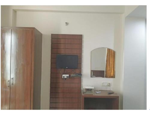 DarbhangaHotel Beena Mansion, Darbhanga的客房设有带镜子的木墙和电视。