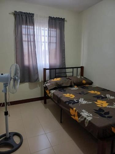 利帕Affordable 2 BR Transient House in Lipa City Batangas的一间卧室配有一张床和一个风扇。