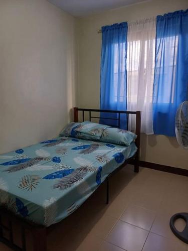 利帕Affordable 2 BR Transient House in Lipa City Batangas的一间卧室配有床和蓝色窗帘的窗户
