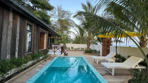 Phumĭ Kaôh Rŭng Sâmlœ̆m KhnŏngOne Beach Private Villa的一个带两把椅子的游泳池以及一座房子