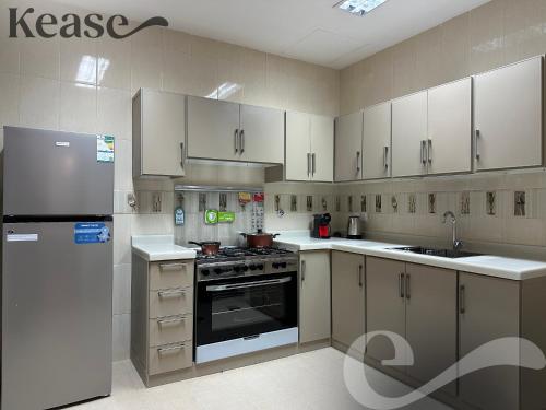 利雅德Kease Al-Mutamarat A-18 Timeless History AX96的厨房配有白色橱柜、炉灶和冰箱。