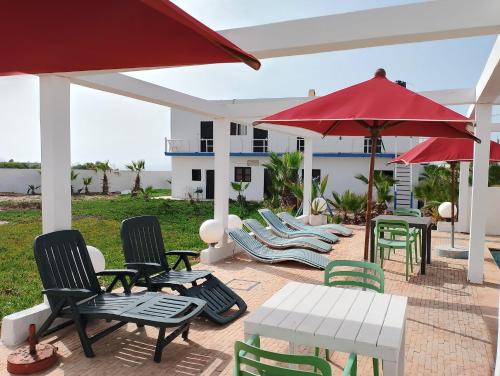 阿加迪尔Riad Ocean Beach Douira的一个带桌椅和红色遮阳伞的庭院