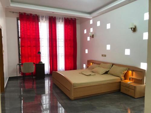Abomey-CalaviMaison d'architecte moderne的一间卧室配有一张带红色窗帘的大床
