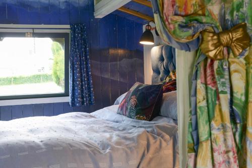 布里德波特Colly Farm的一间卧室配有一张蓝色墙壁的床和一扇窗户
