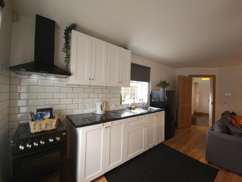 卡索曼Holiday in The Heart of Kerry的厨房配有白色橱柜和黑炉。