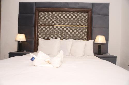 拉合尔Hotel Royal Comfort的一间卧室配有一张带两盏灯的大型白色床。