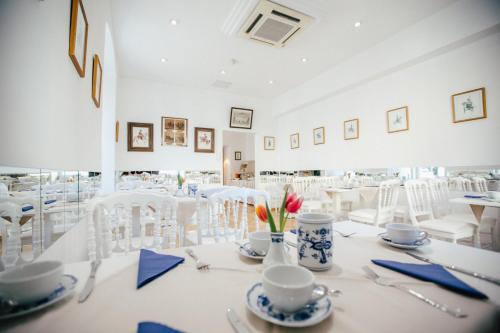 菲拉赫Boutique Hotel Goldenes Lamm的用餐室配有白色的桌子和白色的椅子