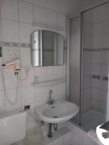 杜塞尔多夫卡洛林格酒店的一间带水槽、淋浴和镜子的浴室