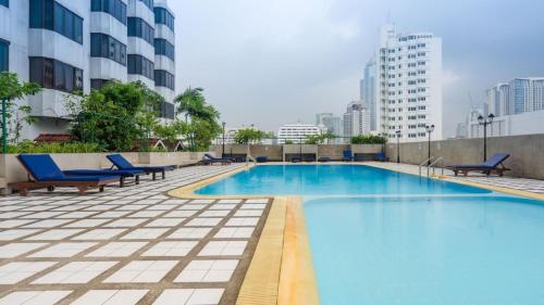 曼谷Omni Tower Sukhumvit Soi 4 Direct Rooms的一座带蓝色椅子的大型游泳池,