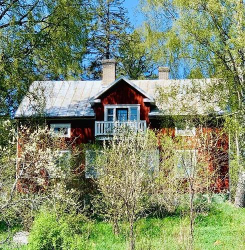 Lantligt boende nära Kastelholms golf och Smakbyn的一座红色的小房子,在田野上设有门廊