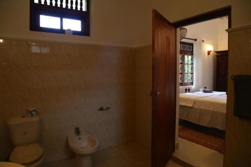 希克杜沃InVilla Hikkaduwa Sri Lanka的一间带卫生间、水槽和床的浴室