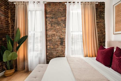 纽约153-5A Charming 2BR LES W D的卧室配有白色的床和砖墙