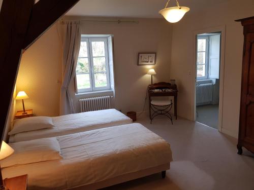 Huisseau-sur-CossonLa Taille de Biou的一间卧室配有两张床、一张桌子和两个窗户。