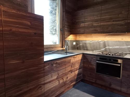 卡罗纳Baita La Piana - Carona的厨房配有木制橱柜、水槽和窗户。