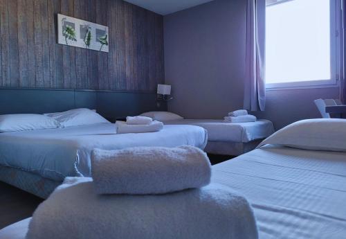 普里瓦Hotel Restaurant Les Chataigniers的酒店客房设有三张床和窗户。