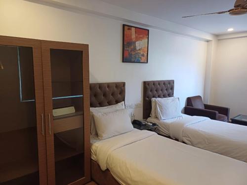 钦奈Hotel Marina Inn Egmore Chennai的酒店客房,配有两张床和椅子