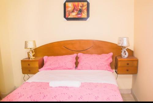 OlmosDominius Hotel的一间卧室配有一张带粉色床单和枕头的床。