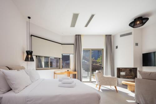 SpílionPanorama Luxury Suites的白色卧室配有一张大床和椅子