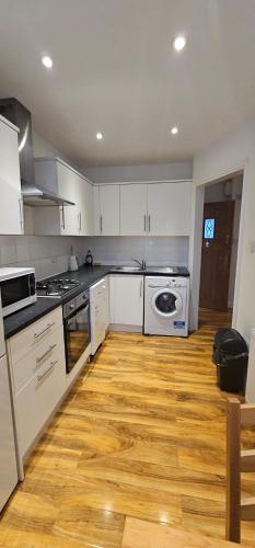 伦敦Kensington Guest Rooms 98的厨房铺有木地板,配有白色橱柜。