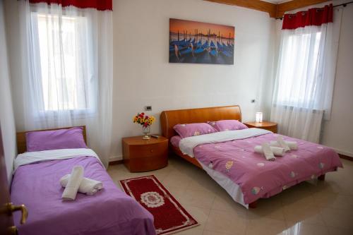 马格拉BB CA VENEZIA的配有紫色床单和白色枕头的客房内的两张床