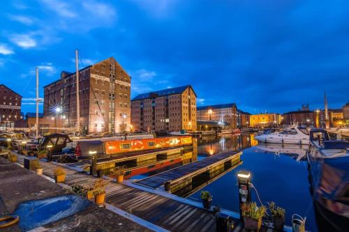 Stylish Ground Floor Apartment Nr Gloucester Docks, by Sauvignon Stays的夜间码头,水中建有建筑物和船只