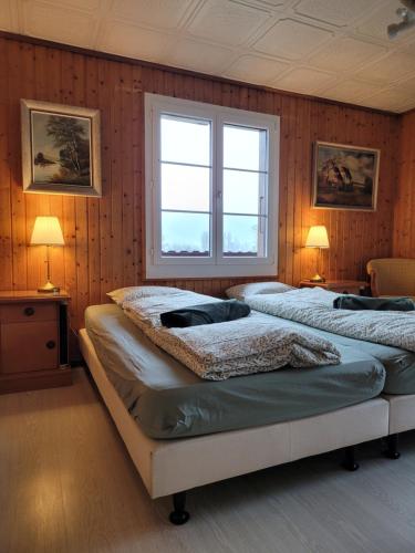 图恩Chalet Nature Park "Apartment Thun"的配有木墙和2扇窗户的客房内的2张床