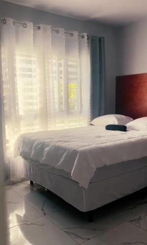 特拉Casa Chavez en Tela的一间卧室配有一张带白色床单的床和一扇窗户。