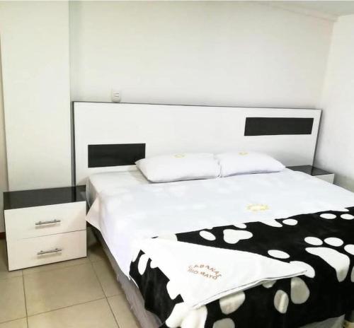 ChachagüíHotel y Cabañas Rio Mayo的一间卧室配有一张带黑白毯子的床