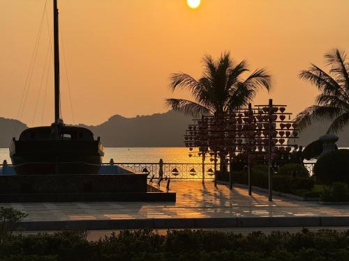 吉婆岛Phoenix Flower Hotel的棕榈树和小船在水面上的日落
