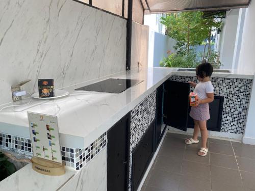 芽庄M Villa Nha Trang的站在厨房里的一个小女孩,