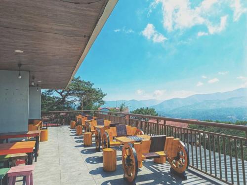 碧瑶Evergreen Suites Cozy Baguio Loft Retreat的阳台上的一排木桌和椅子