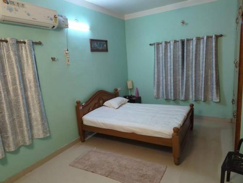 根尼亚古马里Family friendly stay in Kanyakumari town的一间卧室配有一张带蓝色墙壁和窗帘的床