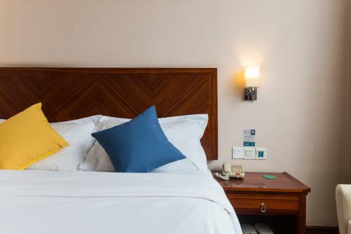 深圳上苑国际酒店(深圳龙华地铁站店)的一间卧室配有蓝色和黄色枕头的床