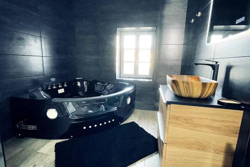 Château-LandonLove Room Le Chalet / Jacuzzi / Sauna的黑色浴室设有木制水槽和浴缸。