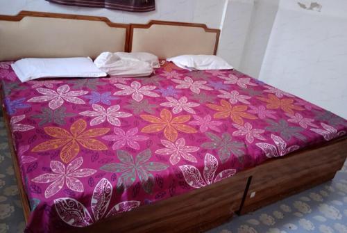 王舍城GRG Kameshwar Bhawan Rajgir的一张带紫色床罩的床,上面有鲜花