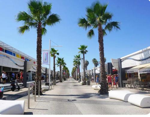 维亚斯Maison de vacances vias plage的一条种有棕榈树的街道,人们沿着人行道走