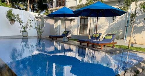高尔Ranil Villa的一个带两把蓝色遮阳伞和两把椅子的游泳池