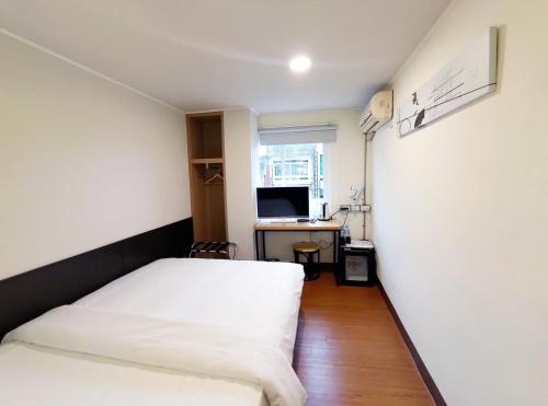 台东富裕商旅 RICH-hotel的一间卧室配有一张床和一张带电脑的书桌
