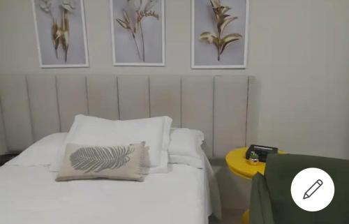 巴西利亚ESPAÇO ACONCHEGANTE NO SUDOESTE的一间卧室配有一张带白色枕头和黄色桌子的床。