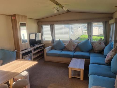 纽基Newquay Bay Porth Caravan - 6 berth的客厅配有蓝色的沙发和电视
