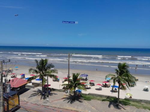 蒙加瓜Belíssimo apartamento frente mar的棕榈树和遮阳伞的海滩和海洋