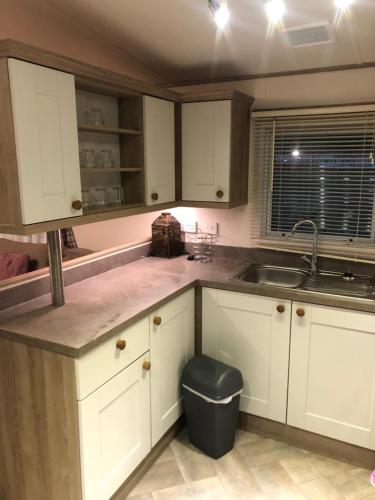 坦伯利Lovely Caravan的厨房配有白色橱柜和水槽