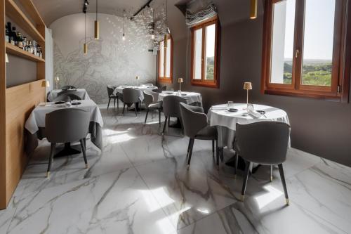 瓦尔多比亚德内Boutique Hotel Municipio 1815的餐厅设有白色的桌椅和窗户。