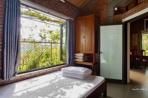 顺化Homestay Mộc Nhi的一间设有大窗户的房间和一张位于房间的床