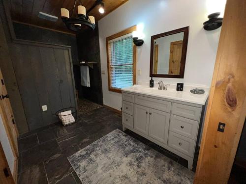 布赖森城Nantahala Nook, cabin w/hot tub,game room, & wifi的一间带水槽和镜子的浴室