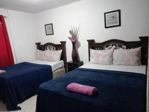 危地马拉Historico maya的一间卧室配有两张带蓝色床单和紫色毛巾的床。